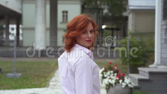 一个红头发的漂亮女人的肖像那个女人慢慢地沿着公园的小路走视频的预览图