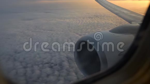 飞机机翼通过飞机窗口的视图日出时在云层上方飞行视频的预览图