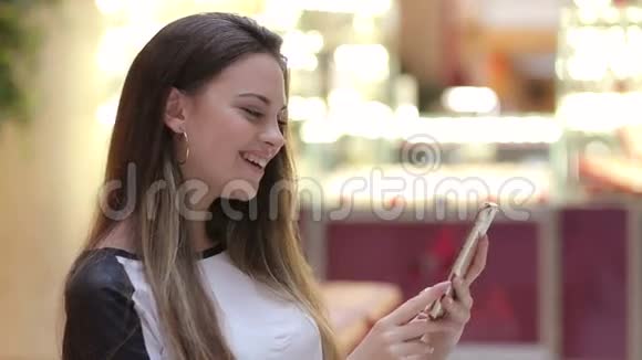 在购物中心带智能手机的微笑女孩视频的预览图