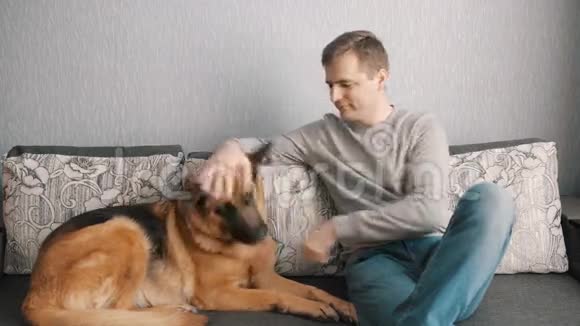 年轻人和他的狗坐在沙发上视频的预览图