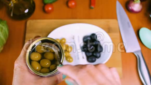 女人手把锡罐里的橄榄放进瓷盘里视频的预览图