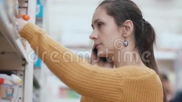 年轻女子站在超市货架前拿着电话说话取项目并征求意见4K视频的预览图