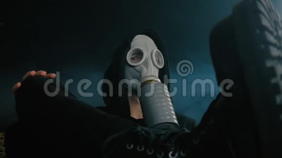 戴着防毒面具的人坐在黑暗的房间里抽烟世界末日后的斯托克视频的预览图
