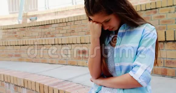 沮丧的女孩坐在校园的楼梯上视频的预览图
