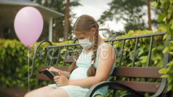 戴呼吸器的可爱女孩在公园里的长凳上用药片视频的预览图