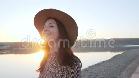 可爱的小女孩戴着帽子在湖边对着镜头微笑视频的预览图