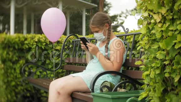 戴呼吸器的可爱女孩在公园里的长凳上用药片视频的预览图