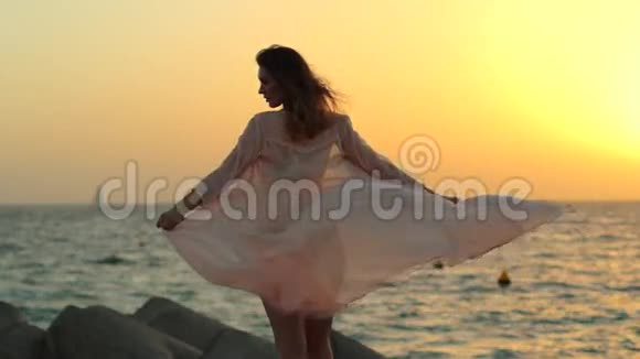 小女孩在石头海滩上玩裙子视频的预览图