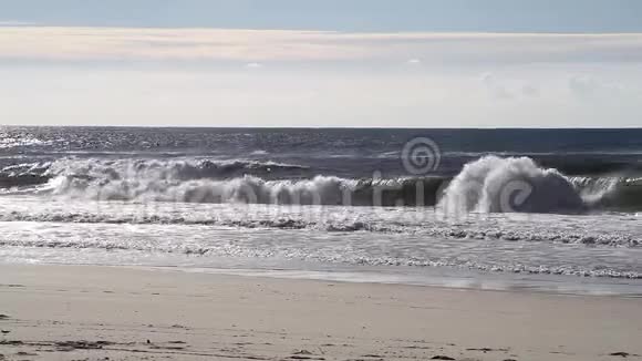 在一个阳光明媚的日子里近距离拍摄海浪向沙滩翻滚的画面视频的预览图