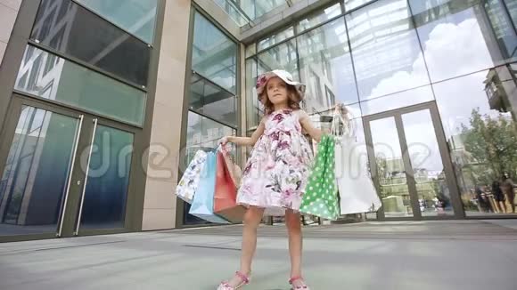 一个快乐的女孩带着鲜艳的袋子转过身喜欢在购物中心附近购物视频的预览图