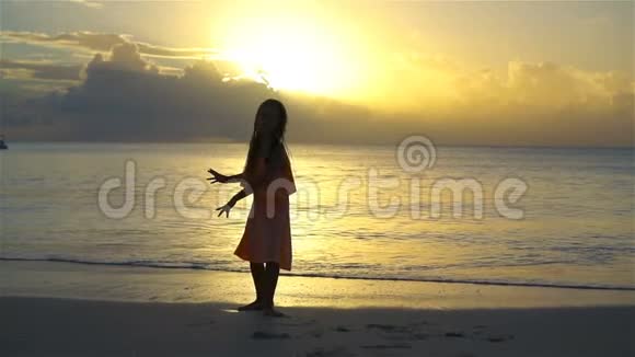 可爱的快乐小女孩在日落的白色海滩上玩得很开心流动人口视频的预览图