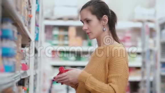 年轻漂亮的女人站在婴儿食品货架前拿着包装婴儿食品选择最好的4K视频的预览图