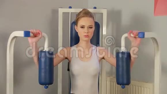 漂亮的金发少女正在健身房里练习胸部和手臂肌肉模拟器视频的预览图