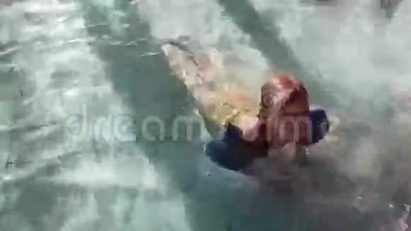 小女孩在水上乐园玩得很开心可爱的女孩带着充气臂躺在池水里顶部视图视频的预览图