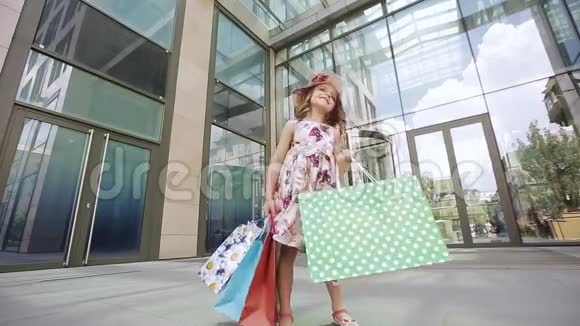 一个快乐的女孩带着鲜艳的袋子转过身喜欢在购物中心附近购物视频的预览图
