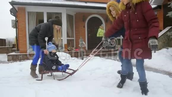 家庭在家后院用雪橇骑男婴的慢动作视频视频的预览图
