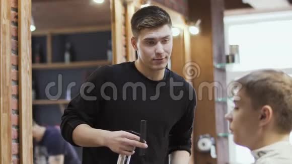 职业造型师在理发店用电动剃须刀剪下年轻人的胡须视频的预览图