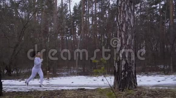 年轻的美女在冬天的森林里慢悠悠地奔跑视频的预览图