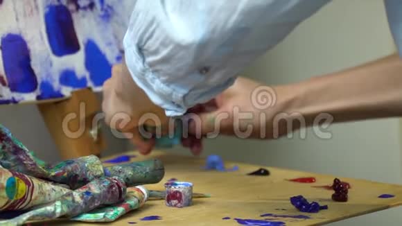 女孩把蓝色的油画颜料挤在一个装满颜料的木调色板上慢镜头拍摄视频的预览图