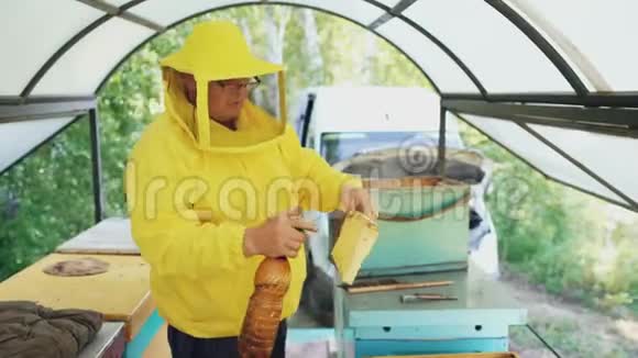 养蜂人用喷雾器给木架浇水并在蜂房内设置视频的预览图