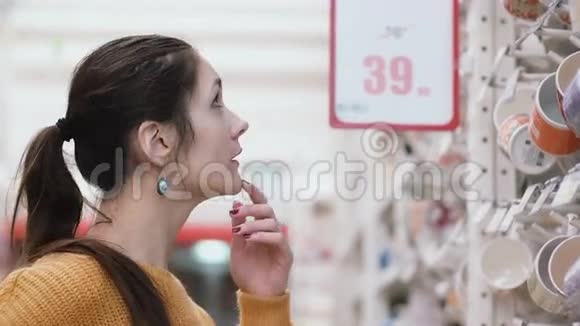 年轻的美女站在超市商店的杯子前试着选择一些东西4K视频的预览图