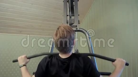 年轻人在家里的健身器材上锻炼他的肌肉视频的预览图