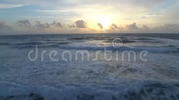 令人惊叹的白云在温暖的早晨日出在平静的白色泡沫海浪卫星冲浪海滩大西洋4k空中视频的预览图