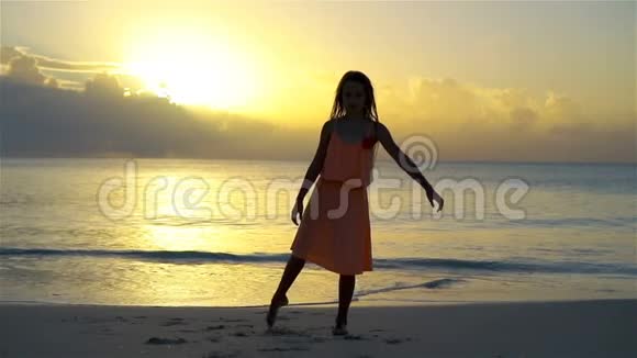 可爱的快乐小女孩在日落的白色海滩上玩得很开心流动人口视频的预览图