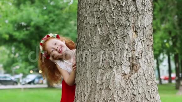 夏天公园里小女孩躲在大树上偷看视频的预览图
