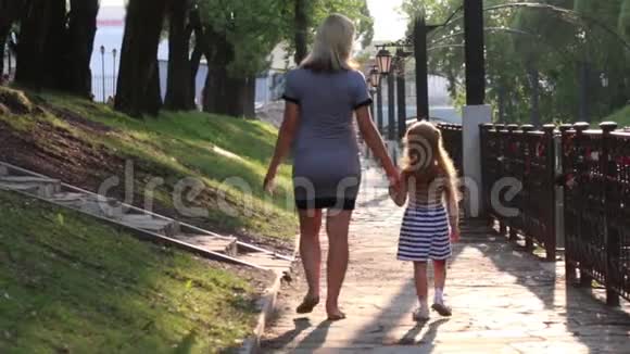 怀孕的母亲和她的小女儿在阳光明媚的公园散步后景视频的预览图