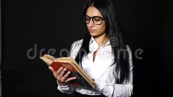 肖像吸引人的女人读书一位年轻漂亮的黑发女郎留着一头长发穿着工作室里视频的预览图