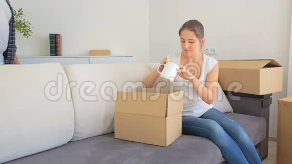 年轻女子把东西装在盒子里男人走进房间给她新房子的钥匙视频的预览图