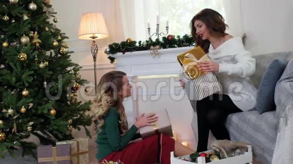 女孩打包礼物两个朋友正坐在客厅的圣诞树旁交谈笑着视频的预览图