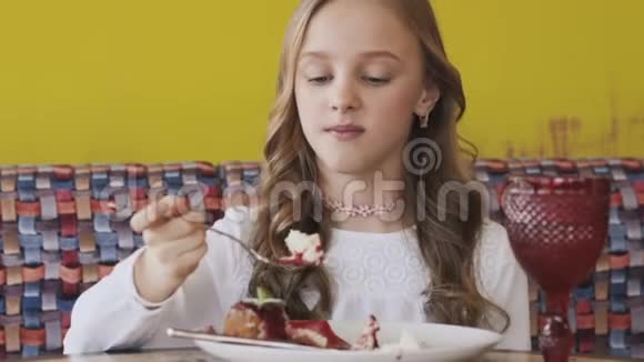 快乐的年轻女孩吃着美味的甜点对着镜头微笑慢慢地视频的预览图