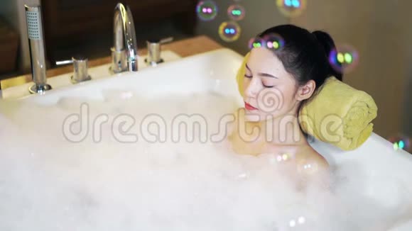 女人放松闭着眼睛在浴缸里漂浮着泡泡视频的预览图