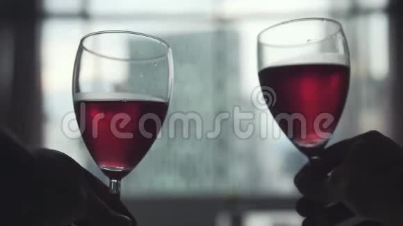 两个人在窗户边碰着一杯红酒看着建筑城市的景色慢动作3840x21604k视频的预览图