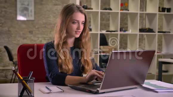 白种人金发女商人在办公室里专心地用笔记本电脑工作的肖像视频的预览图