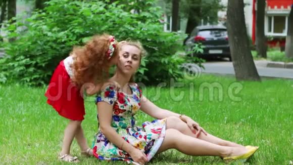 小女孩在夏天公园的草坪上亲吻妈妈视频的预览图