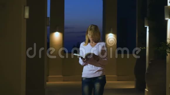 年轻女子用低沉的灯光在大厅里读日记视频的预览图