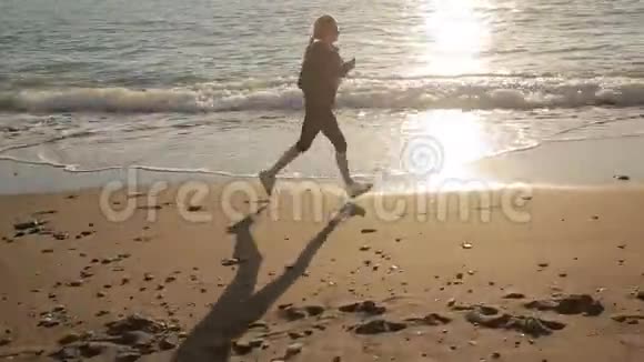 一个穿运动鞋的女人沿着海岸跑向大海逃到海里去视频的预览图