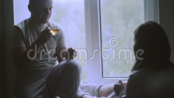 年轻的幸福夫妇拥抱站在窗户附近享受新公寓的景色视频的预览图
