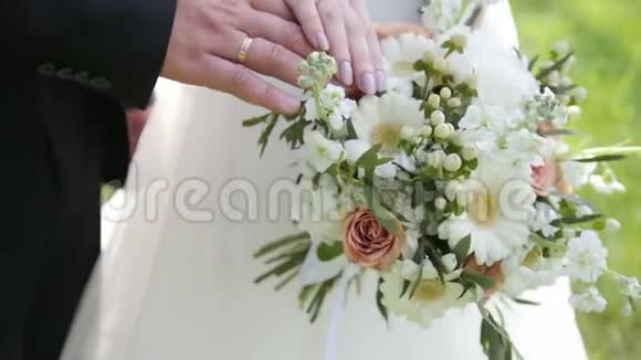 新娘和新郎手里拿着结婚戒指和五颜六色的花束视频的预览图