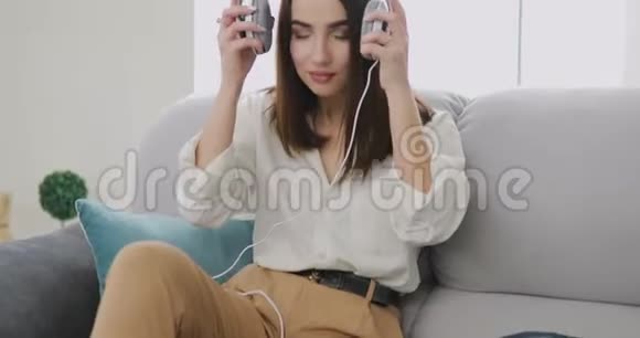 女人在家里用大耳机听音乐视频的预览图