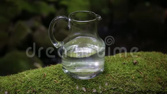 带淡水的玻璃瓶和背景有绿色苔藓的小溪视频的预览图