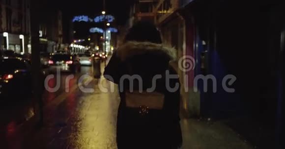 一个黑发长发少女在街上走得很快听着音乐晚上戴着耳机视频的预览图