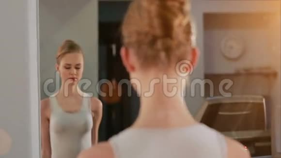 美丽的女孩举起哑铃在锻炼时看着镜子里的自己视频的预览图