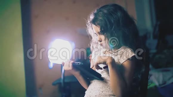 晚上小女孩在室内生活方式的平板电脑上阅读社交媒体帖子儿童和互联网视频的预览图