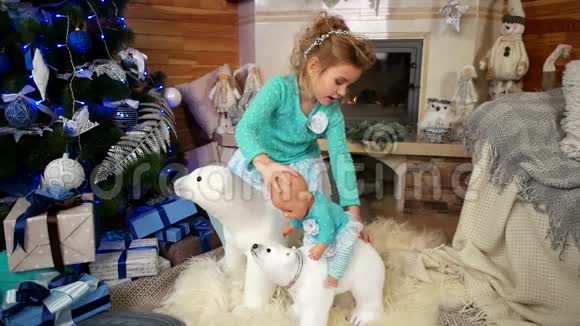 女孩玩洋娃娃孩子在圣诞树附近玩耍除夕夜奇迹的圣诞节玩具视频的预览图