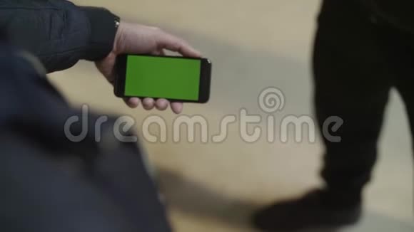 年轻的男性手举着绿色触摸屏的现代智能手机男子手拿手机视频的预览图