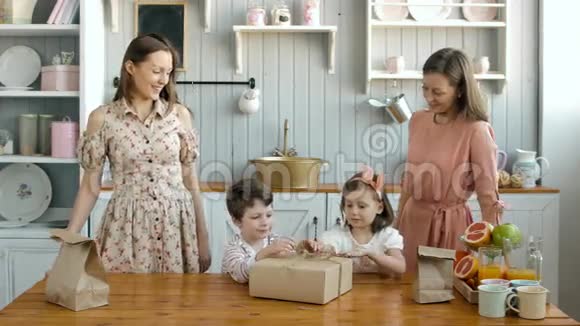 幸福的双胞胎妈妈和他的小女儿女孩和男孩打开厨房的盒子视频的预览图